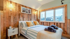 Ein Schlafzimmer mit einem Bett, einem Nachttisch, einem Fenster und Holzverkleidung.