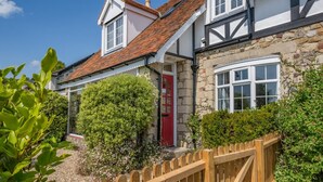 A traditional stone house with a red door, a wooden fence, and a well-maintained garden. - 2 Bed in Ventnor (oc-w30525) (Ventnor)