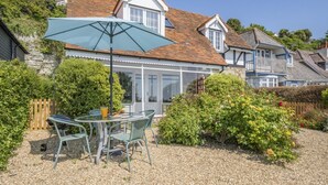 A house with a patio, a table with chairs, and a barbecue grill. - 2 Bed in Ventnor (oc-w30525) (Ventnor)