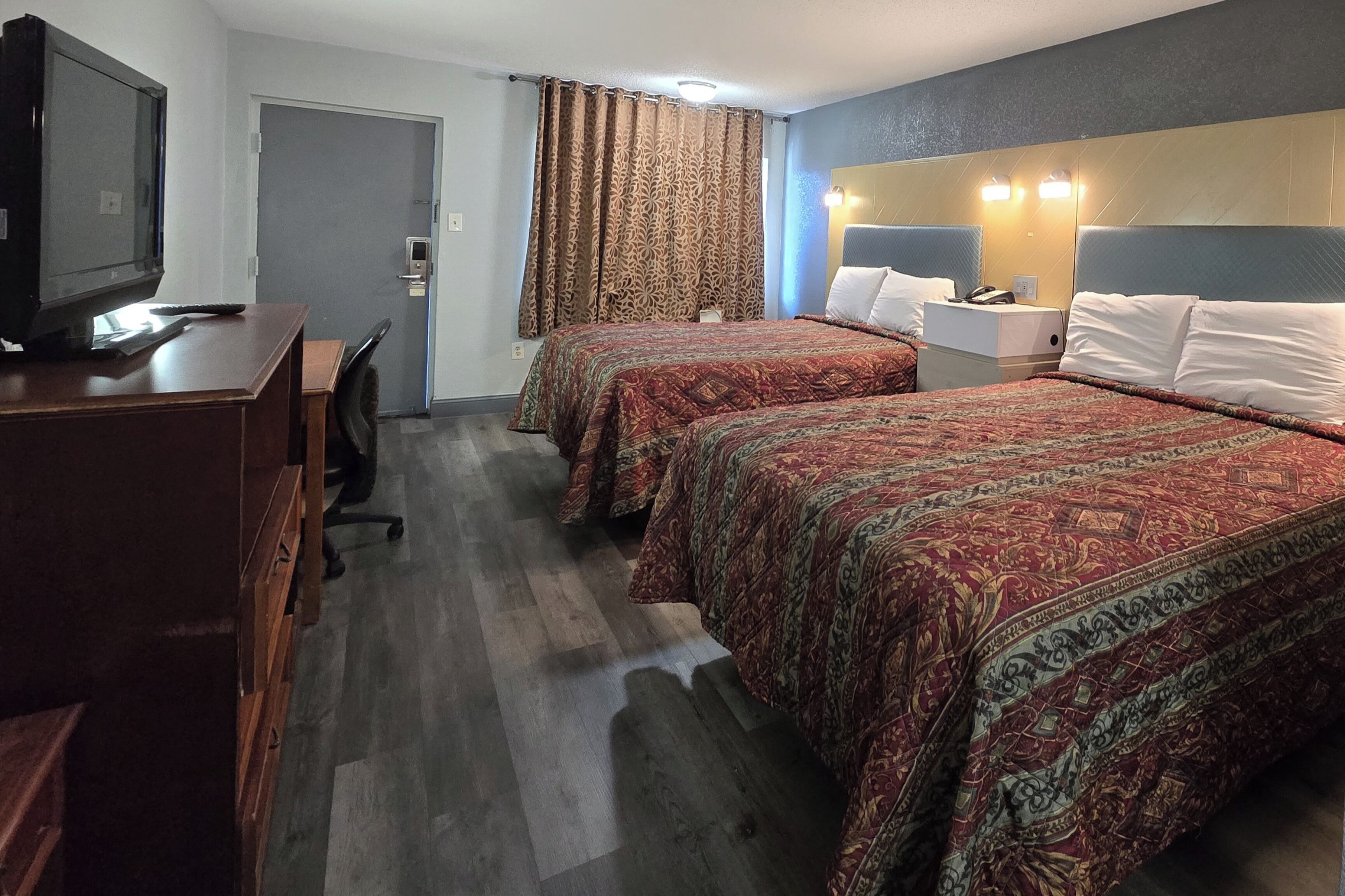 Ett hotellrum med två sängar, ett skrivbord med en tv och en dörr med ett säkerhetslås.
