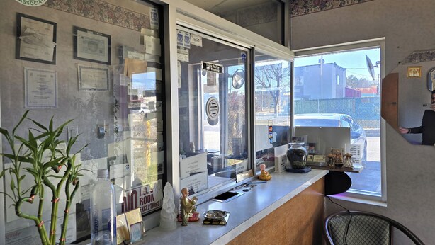 Un espace d’accueil avec un comptoir, des certificats, une plante et une vue sur l’extérieur.