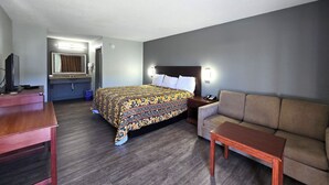 Une chambre d’hôtel comprenant un lit, un canapé, une petite table, un bureau et une salle de bain avec un miroir et un lavabo.