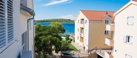 A coastal residential area with a clear view of the sea, a paved street, and a parked car.