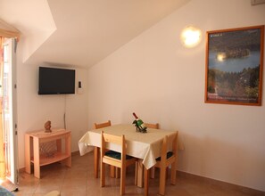 A dining area with a table set for four, a bottle of wine, and a painting on the wall. - Apartments Gabi - Two Bedroom/balcony/sea view(B3) (Srima)