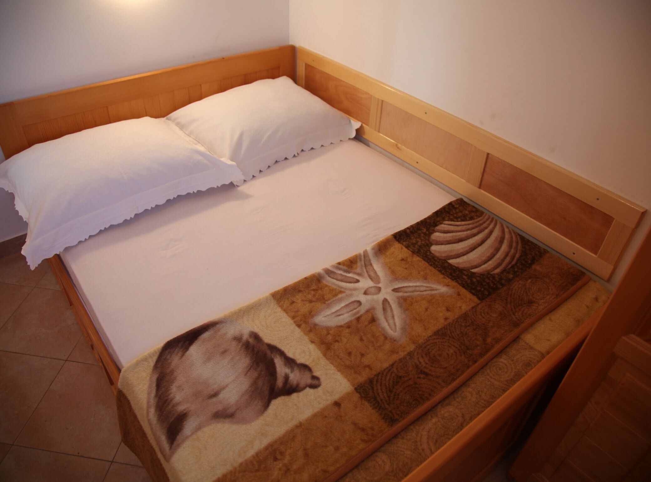 A single bed with a wooden headboard and a white pillow.