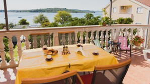A terrace with a yellow table set for breakfast, overlooking a lake and greenery. - Apartments Gabi - One Bedroom/balcony/sea view(B4) (Srima)