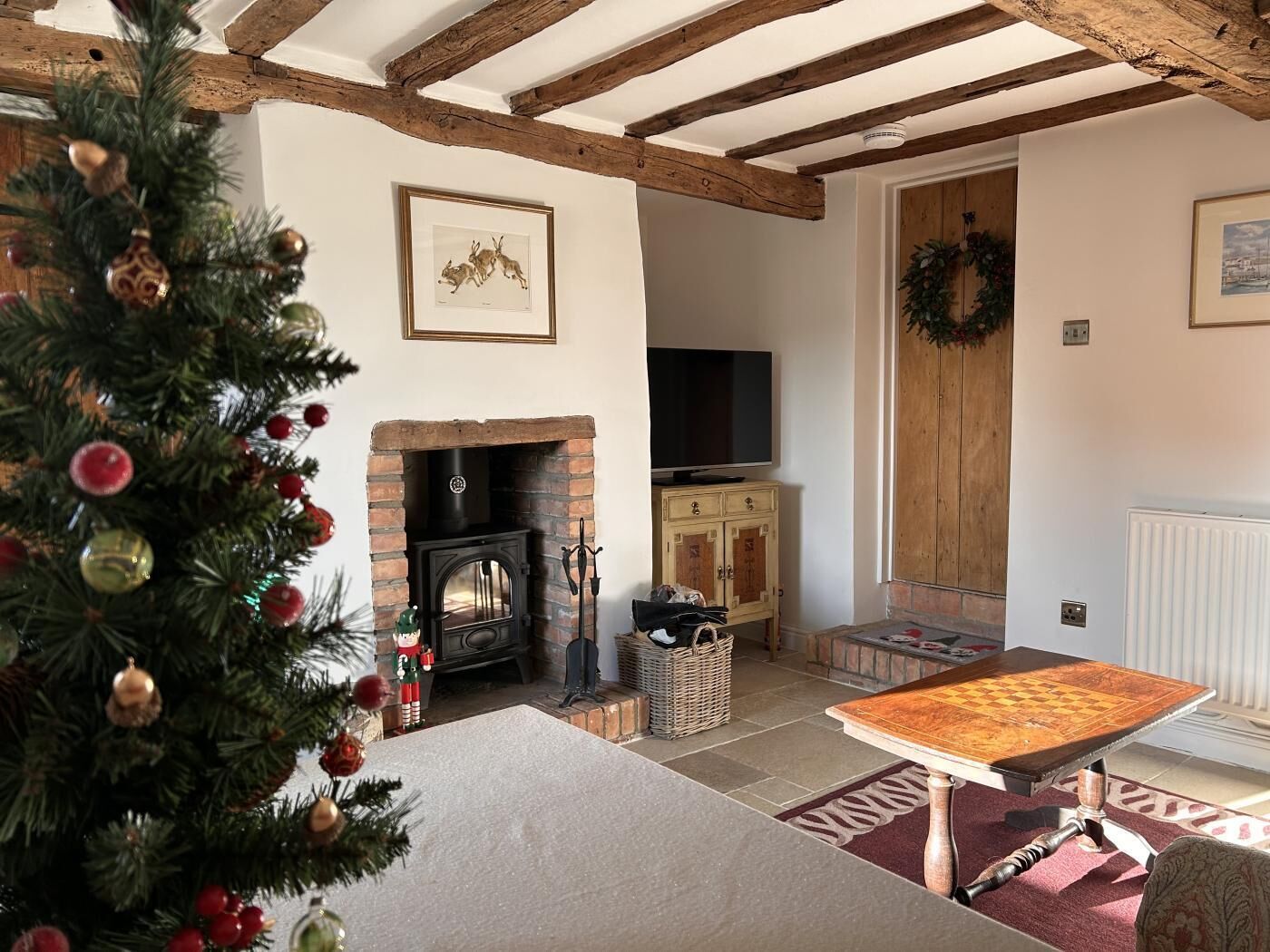 Een gezellige woonkamer met een open haard, een televisie en een kerstboom.