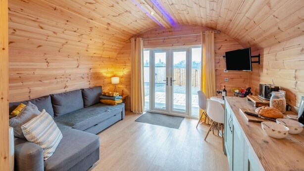 A cozy cabin interior with a sofa, a dining area, and a TV mounted on the wall. - 1 Bed in East Cowton (oc-w30480) (East Cowton)