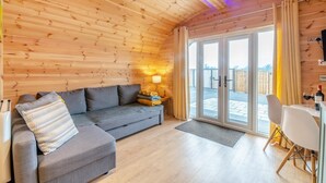 A cozy wooden cabin interior with a sofa, a table with chairs, and a sliding glass door leading to an outdoor area. - 1 Bed in East Cowton (oc-w30480) (East Cowton)