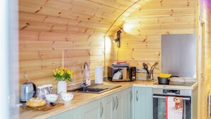 A compact kitchen with wooden walls, a sink, a microwave, a stove, and a small window with a teddy bear decoration. - 1 Bed in East Cowton (oc-w30480) (East Cowton)