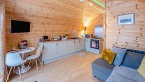 Una habitación acogedora tipo cabaña con kitchenette, comedor y sofá.