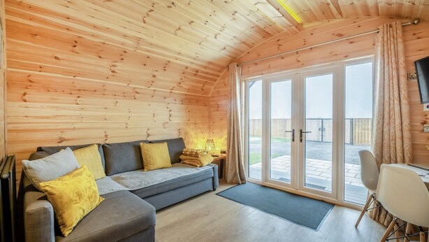 Una habitación acogedora con sofá, una mesa de comedor y un amplio ventanal corredero que da a un espacio exterior.