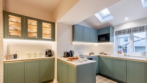 Una cocina moderna con gabinetes verdes, una isla central y un tragaluz.