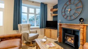 Un salón con chimenea, un reloj de pared grande y un televisor.