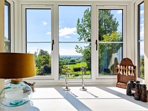 A room with a large window offering a view of a green landscape.
