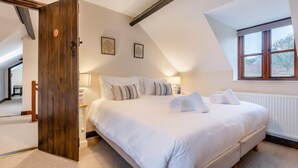 Un dormitorio con una cama grande, una puerta de madera, una ventana y un radiador.