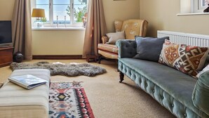 Una sala de estar acogedora con un sofá, un sillón y una alfombra.