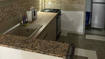 Una cucina con piano di lavoro in granito, piano cottura a gas, frigorifero in acciaio inossidabile e backsplash in piastrelle.