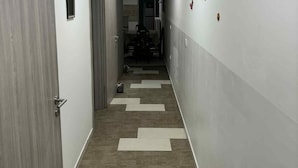 Un pasillo con piso estampado, una puerta a la izquierda y un muro con interruptor de luz a la derecha.