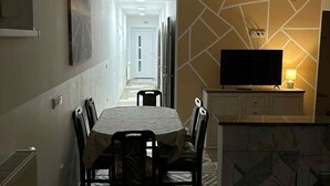 Un comedor con una mesa y sillas, un televisor sobre un mueble bajo y un muro con diseño.
