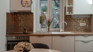 Une cuisine moderne avec un mur recouvert de pierres, une fenêtre donnant sur un paysage verdoyant et un vase de fleurs posé sur la table.