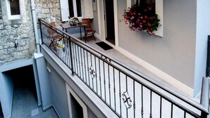 Un balcon orné d’une balustrade en fer forgé, d’un mur en pierre et d’une jardinière fixée au mur.