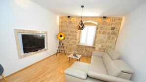Un salon moderne avec un mur en pierre, un grand canapé, un téléviseur et un lampadaire.