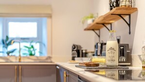 Une cuisine moderne avec une bouteille de lait étiquetée « Midtown Milkhouse Calbeck » posée sur le comptoir, un grille-pain et une plante en arrière-plan.