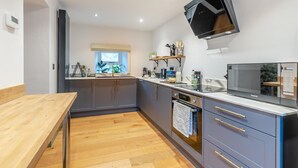 Une cuisine moderne avec des meubles gris, une table à manger en bois et un micro-ondes encastré.