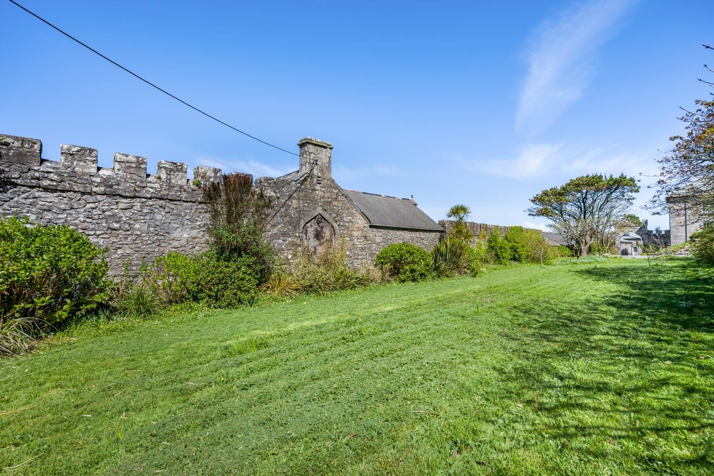 A stone building with a grassy lawn and a stone wall.