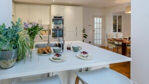 Eine moderne Küche mit weißen Schränken, Edelstahlgeräten und einer Frühstücksecke auf der Arbeitsplatte.
