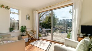 Ein geräumiges Wohnzimmer mit einem großen Schiebeglastür, die auf eine Außenpatio führt.
