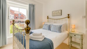 Une chambre d’hôtel avec un grand lit, une vue sur les bâtiments environnants, une table de chevet avec une lampe et une fenêtre avec des rideaux.