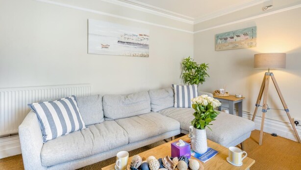 Un salon moderne avec un canapé gris, une table basse en bois et un lampadaire.