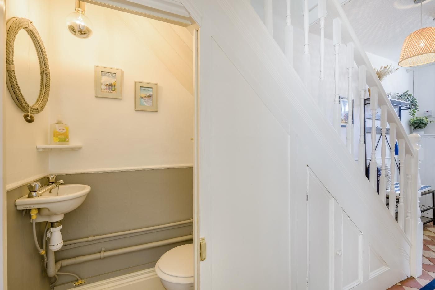 A bathroom with a white sink, toilet, and bathtub, a mirror, and two framed pictures on the wall.
