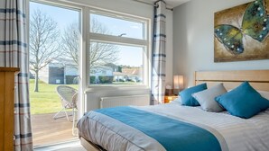 Ein Schlafzimmer mit einem großen Bett, Blick ins Freie und einem Schmetterlingsbild an der Wand.