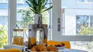 Ein Esstisch mit Croissants, Beeren und einem Einmachglas Müsli.