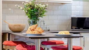 Eine Küche mit einer Holtschale, einem Teller mit Croissants, einer Vase mit Blumen und einer Mikrowelle.