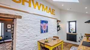 Tilava huone, jossa on korkea katto, kattovalokuvio ja suuri seinälle kiinnitetty kyltti, jossa lukee: ”SHWMAE”.