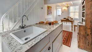 Una cucina con un piano di lavoro in granito, un lavandino bianco e una scala in legno.