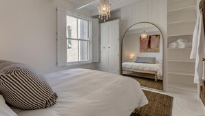 Una camera da letto con un letto grande, una finestra, uno specchio e un lampadario.