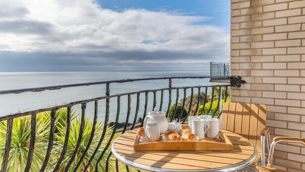Een balkon met een ontbijtje gedekt, met uitzicht op een wateroppervlak.