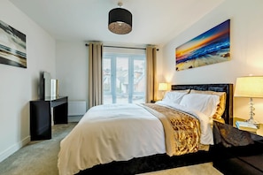 A hotel room with a bed, a desk, a lamp, a painting, and a window with curtains. - 4 Bed in Seaton (oc-a89856) (Seaton)