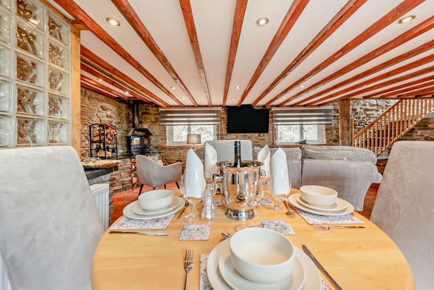 A dining area with a wooden table set for four, surrounded by cushioned seating.