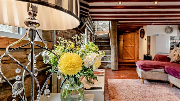 Uma sala de estar com um sofá branco, uma luminária decorativa e um vaso de flores.