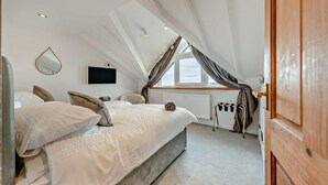 Quarto com uma cama grande, televisão, janela com cortinas e radiador.