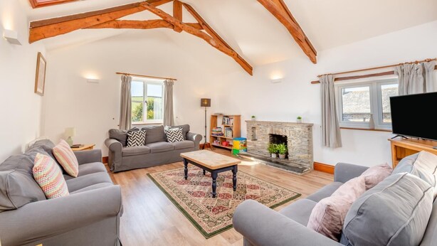 A spacious living room with a high ceiling, a fireplace, a television, and a cozy seating area. - 4 Bed in East Allington (oc-k30711) (East Allington)