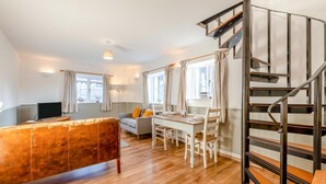Un salon moderne avec un plancher en bois, un canapé, une table à manger avec des chaises et un escalier.