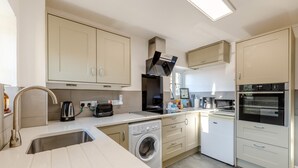 Une cuisine moderne équipée d’un lave-linge, d’un four encastré et d’un four à micro-ondes.
