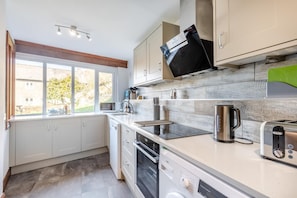 Une cuisine moderne avec des meubles blancs, un four encastré, un four à micro-ondes et un grille-pain.